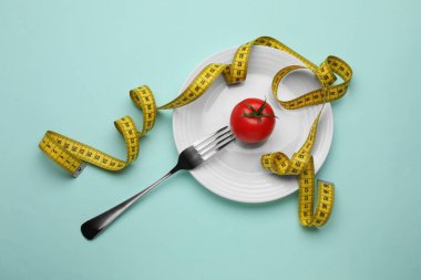Tabak, domates, çatal ve turkuaz arka plan mezurası, üst manzara. Diyet kavramı