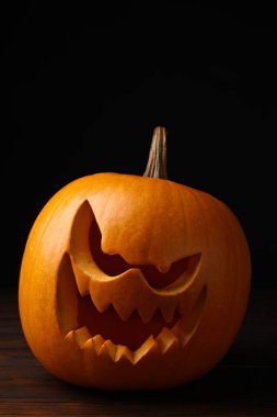 Karanlıkta tahta masanın üzerinde balkabağından yapılmış korkunç Jack O 'Lantern. Geleneksel Cadılar Bayramı dekorasyonu