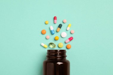 Turkuaz arka planda bir sürü farklı ilaç içeren plastik tıbbi şişe.