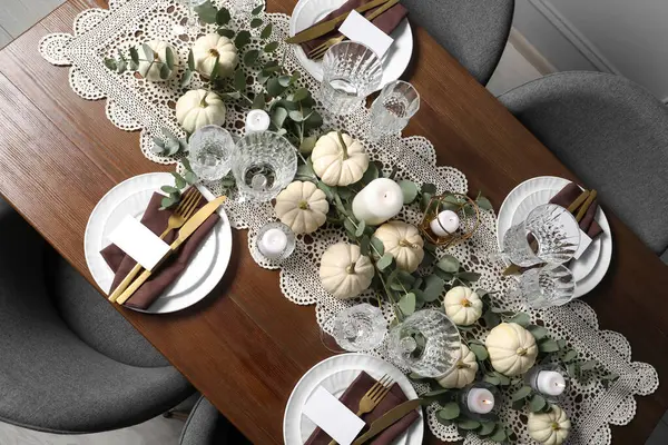 Güzel bir sonbahar sofrası. Tabaklar, çatal bıçak takımı, bardaklar, boş kartlar ve çiçek dekoru.