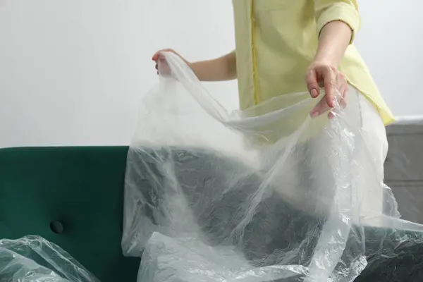 Mulher Colocando Filme Plástico Longe Poltrona Perto Parede Clara Dentro — Fotografia de Stock
