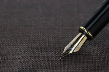Koyu desenli yüzeye yakın çekimde süslü dolma kalem. Metin için boşluk