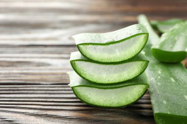 Ahşap masada taze aloe vera parçaları, yakın plan. Metin için boşluk