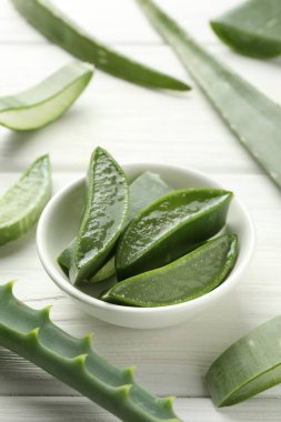 Taze aloe vera parçaları beyaz ahşap masada, yakın plan.