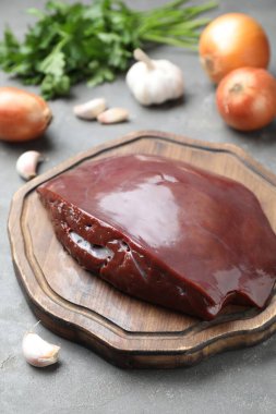 Çiğ sığır ciğeri ve ürünleri gri masada, yakın plan.