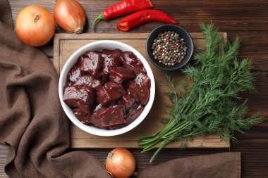 Çiğ sığır ciğerini soğan, baharat, kırmızı biber ve ahşap masada dereotla kes.