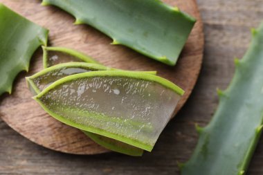 Dilimlenmiş taze aloe vera yaprakları ve ahşap masa üzerinde jöle, düz uzanmış. Metin için boşluk