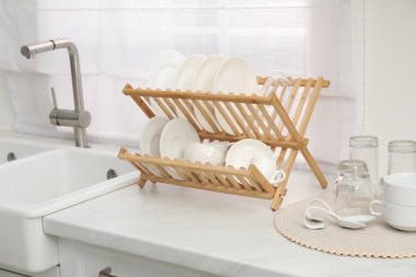 Mutfak lavabosunun yanındaki açık mermer tezgahta temiz tabaklarla kuru askı.