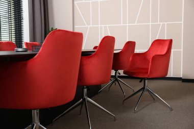 Boş konferans odasında şık kırmızı ofis sandalyeleri ve büyük masa