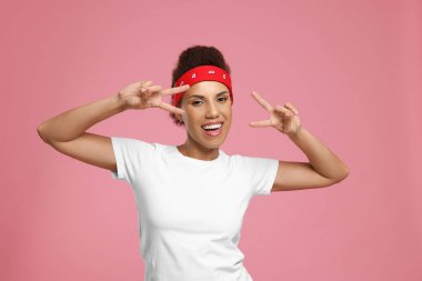 Pembe arka planda dans eden şık saç bandı takan mutlu genç kadın.