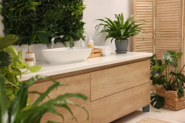 Yeşil yapay bitkiler, makyaj malzemeleri ve banyoda farklı kişisel bakım ürünleri.