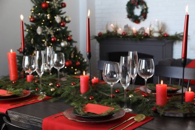 Şenlikli bir odada bulaşık takımı ve yanan mumlarla şık bir Noel sofrası.