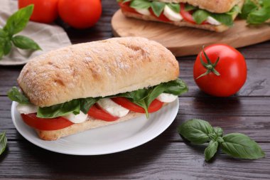Nefis Caprese sandviçi, mozarella, domates ve ahşap masada fesleğen.