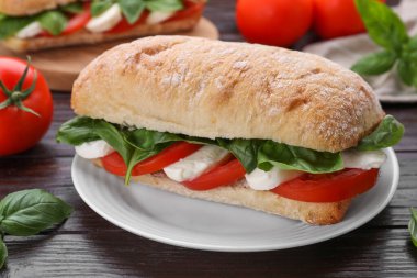 Nefis Caprese sandviçi, mozarella, domates ve fesleğen, ahşap masa, yakın plan.