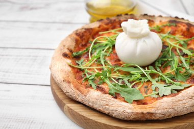 Burrata peynirli lezzetli pizza ve beyaz ahşap masada roka, yakın plan.