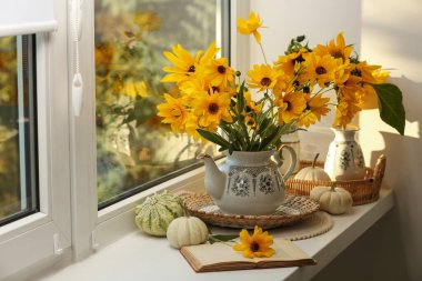Güzel çiçekli kompozisyon, balkabağı ve pencere kenarında kitap. Sonbahar atmosferi