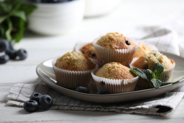 Yaban mersinli lezzetli çörekler ve beyaz ahşap masada nane şekeri, yakın plan.