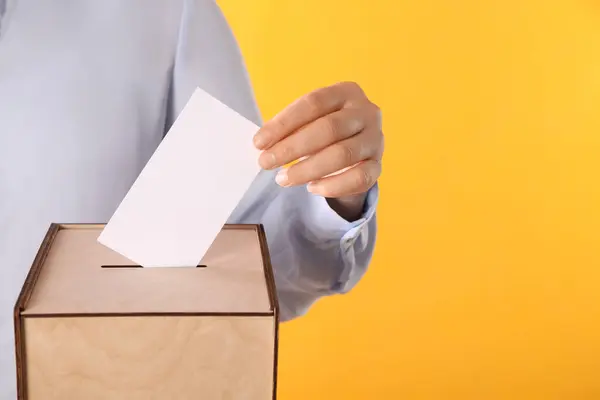 Vrouw Zet Haar Stem Stembus Oranje Achtergrond Close Ruimte Voor — Stockfoto