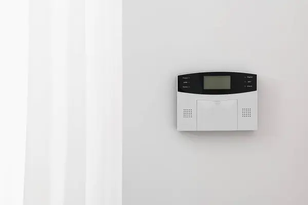 Home security alarm system on white wall indoors, space for text