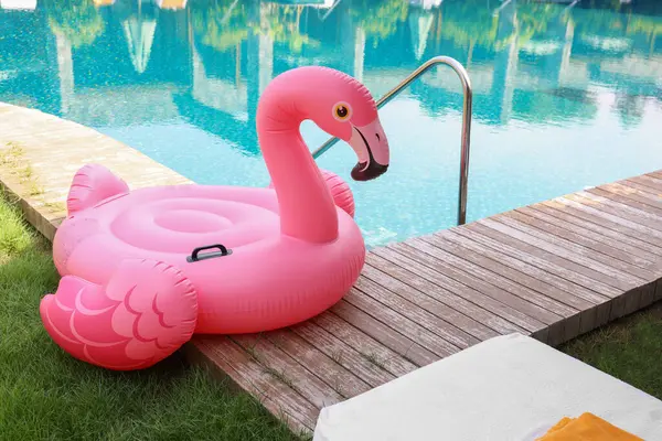 Lüks bir tatil köyünde yüzme havuzunun yanındaki tahta güvertede flamingo şeklinde süzül.