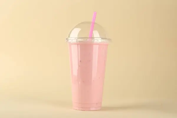 Plastic cup of tasty smoothie on beige background