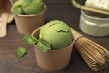 Lezzetli kibrit dondurmalı kağıt bardaklar ve ahşap masada bambu çırpıcı, yakın plan.