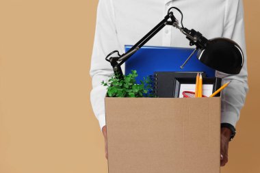 Bej arka planda kişisel ofis eşyaları kutusuyla işsiz genç adam, yakın plan. Metin için boşluk