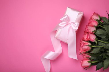 Pembe arka planda fiyonklu ve güllü güzel hediye kutusu, düz yatıyordu. Metin için boşluk