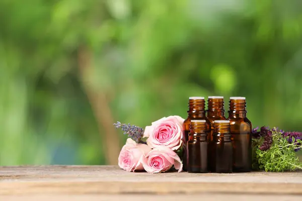 Bottles Essential Oils Herbs Flowers Wooden Table Blurred Green Background — Stock Photo, Image