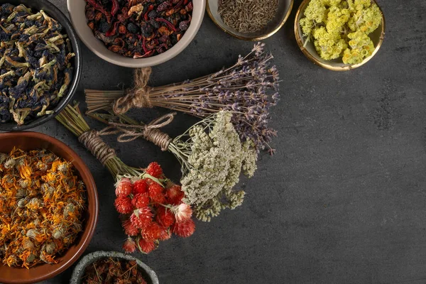 Many different dry herbs and flowers on dark grey table, flat lay. Space for text