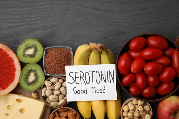 Many different products and card with phrase Serotonin Good Mood on grey wooden table, flat lay. Natural antidepressants