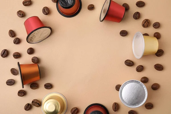 Frame made of many coffee capsules and beans on beige background, top view. Space for text