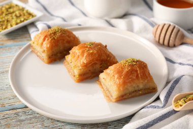 Açık mavi ahşap masada fıstıklı enfes tatlı baklava, yakın plan.