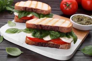 Nefis Caprese sandviçleri, mozarella, domates ve ahşap masada fesleğen.