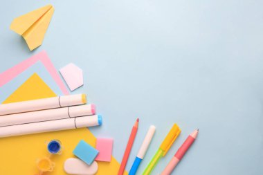 Açık mavi zemin üzerinde farklı okul kırtasiyesine sahip düz kompozisyon, metin için boşluk. Okula geri dön.