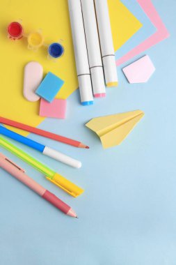 Açık mavi zemin üzerinde farklı okul kırtasiyesine sahip düz kompozisyon, metin için boşluk. Okula geri dön.