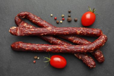 Bir sürü kuru füme sosis, karabiber ve domatesler siyah masada, düz yatıyordu.