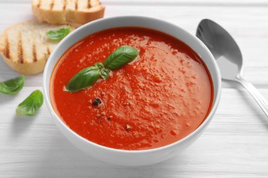 Lezzetli domates kremalı çorba beyaz ahşap masada, yakın plan.