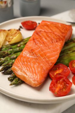 Lezzetli ızgara somon, kuşkonmaz, domates ve limon, yakın plan.