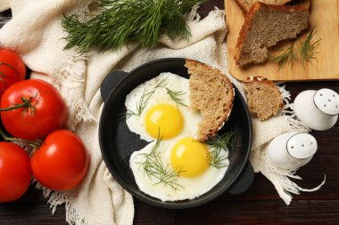 Tahta masada ekmek ve domateslerle servis edilen leziz sahanda yumurtalar.