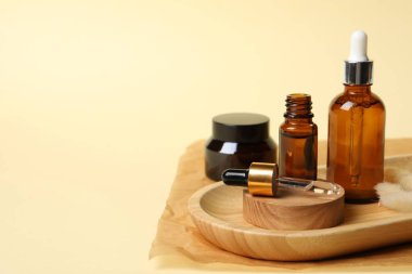 Bej arka planda kozmetik serumu şişeleri olan bir kompozisyon. Metin için boşluk