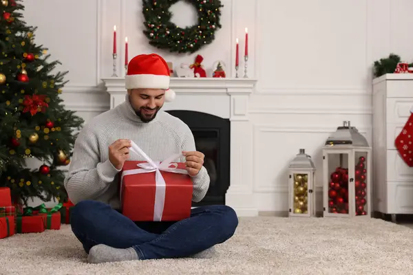 Счастливый Молодой Человек Шляпе Санты Открывает Рождественский Подарок Дома — стоковое фото