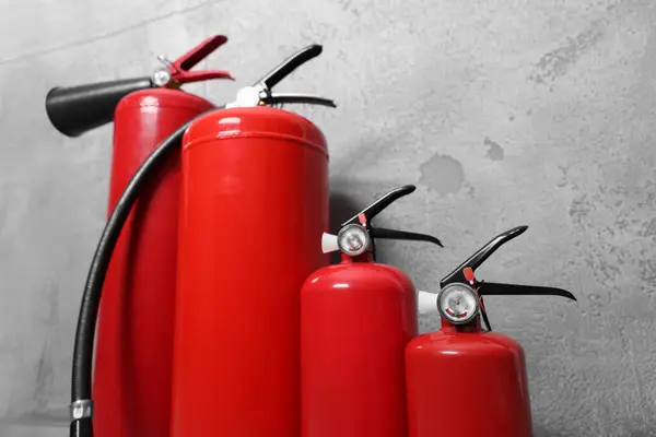 stock image Four red fire extinguishers near grey wall