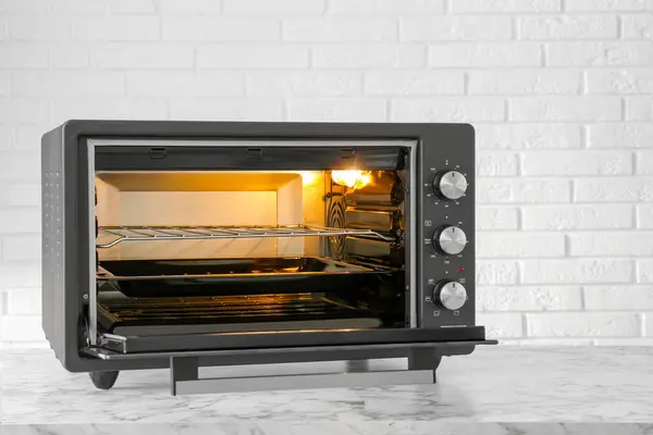 One electric oven on white marble table near brick wall