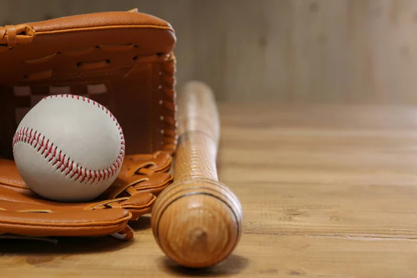 Baseball glove, bat and ball on wooden table, closeup. Space for text