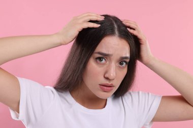 Pembe arka planda kepek sorunu olan duygusal bir kadın.