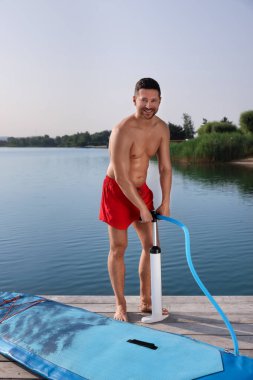 İskelede SUP panosunu şişiren adam