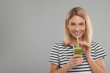 Açık gri arka planda bir bardak taze kereviz suyu ile mutlu bir kadın. Metin için boşluk