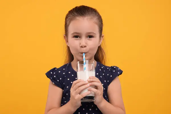 オレンジ色の背景にガラスから新鮮なミルクを飲むかわいい少女 — ストック写真