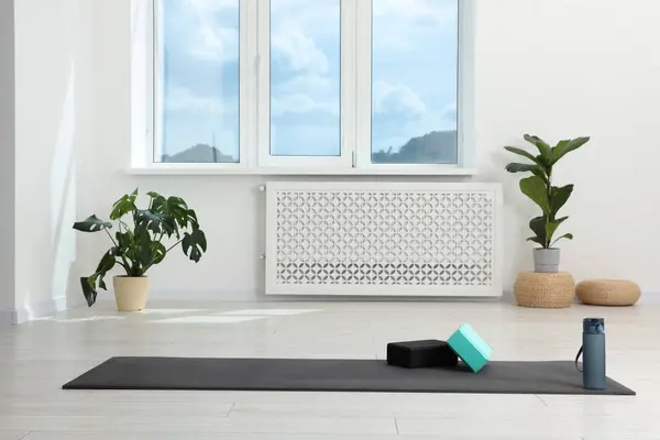 Exercise mat, yoga blocks and bottle of water on floor in room